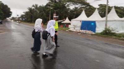 Walau Diguyur Gerimis, Satlantas Tetap Sigap Bantu Pelajar Menyebrang Jalan